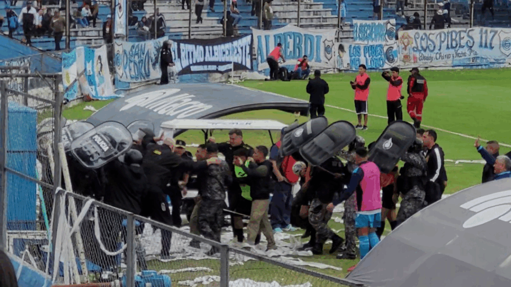 El árbitro Lucas Comesaña se retira escoltado por la policía tras el primer tiempo en el estadio 23 de Agosto.